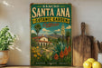 A vintage-style sign for the Rancho Santa Ana Botanic Garden in California, featuring a colorful illustration of a desert landscape with a house and various plants.