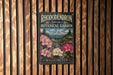 A vintage-style metal sign for the Rhododendron Species Botanical Garden in Washington, featuring a scenic landscape with a mountain backdrop and colorful flowers.