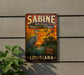 A vintage metal sign for the Sabine National Wildlife Refuge in Louisiana, featuring an illustration of a heron and a sunset landscape.