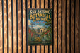 A vintage-style metal sign for the San Antonio Botanical Garden in Texas, featuring a colorful illustration of the garden and a windmill.