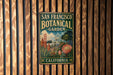 A vintage-style metal sign for the San Francisco Botanical Garden in California, featuring a colorful illustration of the garden's landscape and iconic landmarks.