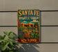 A vintage-style metal sign for the Santa Fe Botanical Garden in New Mexico, featuring a colorful illustration of desert plants and a building.