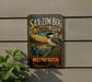 a vintage-style metal sign with a bird illustration, mounted on a wall next to a plant.
