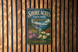 A vintage metal sign for Shore Acres State Park Garden in Oregon, featuring a scenic landscape with flowers and a body of water.