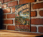 A vintage-style sign for Sonnenberg Gardens in Canandaigua Lake, New York, featuring a scenic illustration of a garden with a gazebo and a lake.