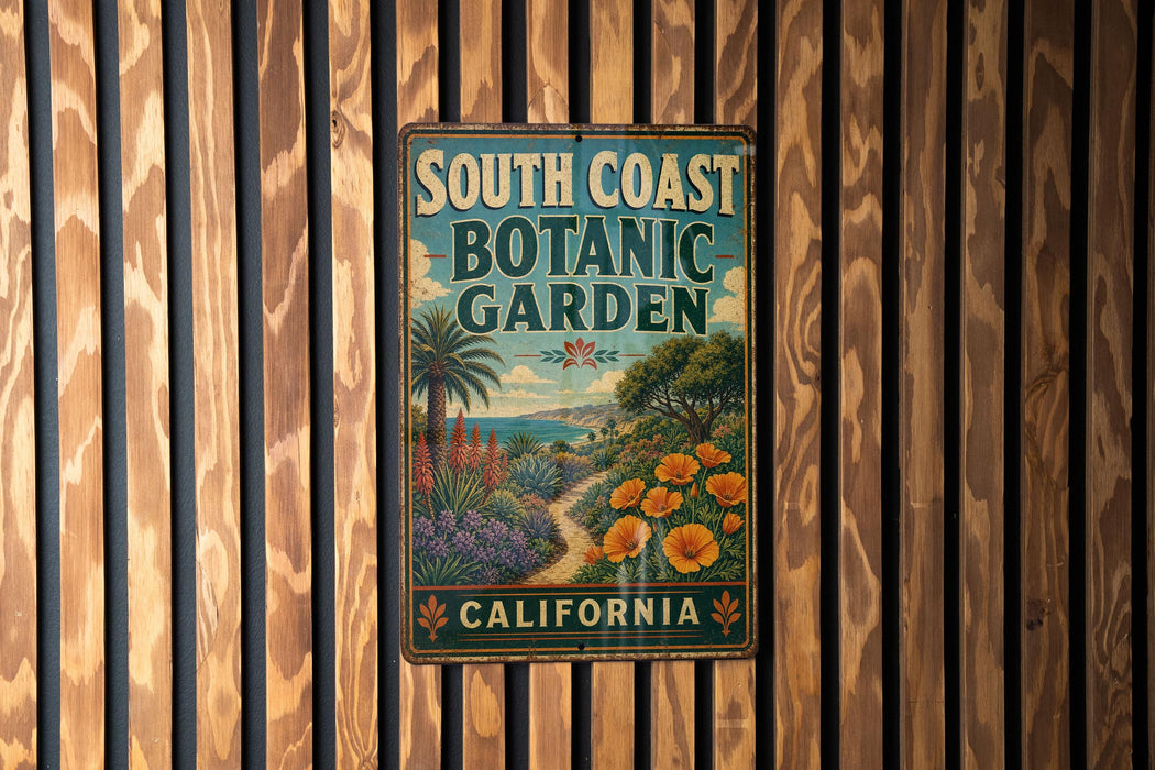 A vintage-style metal sign for the South Coast Botanic Garden in California, featuring a tropical garden scene with palm trees, flowers, and a winding path.