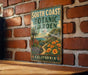 A vintage-style metal sign for the South Coast Botanic Garden in California, featuring a tropical garden scene with palm trees, flowers, and a winding path.