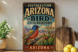 A vintage-style sign for the Southeastern Arizona Bird Observatory, featuring a colorful illustration of a bird perched on a cactus plant.