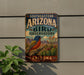A vintage-style sign for the Southeastern Arizona Bird Observatory, featuring a colorful illustration of a bird and desert landscape.