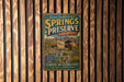 A vintage-style metal sign for Springs Preserve, Nevada, featuring a scenic image of the preserve surrounded by natural landscapes and a building.