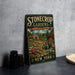 A vintage-style metal sign for "Stonecrop Gardens" in New York, featuring a garden scene with a house, flowers, and a waterfall.