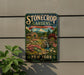 A vintage-style sign for "Stonecrop Gardens" in New York, featuring a garden scene with a house, flowers, and a waterfall.