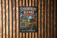 A vintage metal sign for Strawberry Bank Museum Gardens in New Hampshire, featuring a colorful illustration of a historic house surrounded by flowers.