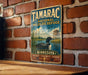 A vintage metal sign for the Tamarac National Wildlife Refuge in Minnesota, featuring a duck swimming in a lake and surrounded by trees.