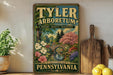 A vintage-style sign for "TYLER ARBORETUM" is displayed on a shelf, featuring a scenic landscape with a bridge and flowers.