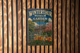 A vintage metal sign for the Winterthur Museum and Garden in Delaware, featuring a colorful illustration of a historic building surrounded by flowers and a pond.