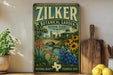 A vintage-style metal sign for the Zilker Botanical Garden in Austin, Texas, featuring a scenic illustration of the garden with a bridge, flowers, and a city skyline.