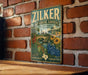 A vintage-style metal sign for the Zilker Botanical Garden in Austin, Texas, featuring a colorful illustration of various plants and flowers.