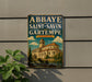 A vintage-style sign for the Abbaye de Saint-Savin in Gartempe, France, featuring an illustration of a church with a tower and a blue sky with clouds.