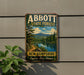 A vintage metal sign for Abbott State Forest in New Hampshire, featuring a scenic landscape with a lake and mountains.