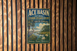 A vintage-style sign for the Ace Basin National Estuarine Research Reserve in South Carolina, featuring a blue background with a white bird and a serene landscape.