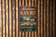 A vintage-style metal sign for Alabama's Black Belt National Heritage Area, featuring a scenic image of a cotton plantation and a house.