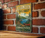 A vintage-style metal sign for Algonquin State Forest in Connecticut, featuring a scenic landscape with a lake, mountains, and a red canoe.