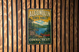 A vintage metal sign for Algonquin State Forest in Connecticut, featuring a scenic illustration of a lake, forest, and canoe.