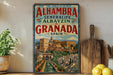 A vintage-style poster of Alhambra, Spain, featuring the city's iconic architecture and landscape, is displayed on a wall next to a wooden cutting board and some potted plants.