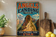 A vintage-style sign for the Angels Landing Trail in Zion National Park, Utah, featuring a scenic mountain landscape.