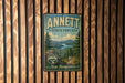 A vintage metal sign for the Annett State Forest in New Hampshire, featuring a scenic landscape with pine trees and a river.