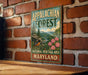 A vintage metal sign for the Appalachian Forest National Heritage Area in Maryland, featuring a scenic illustration of the forest and mountains.