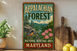 A vintage-style sign for the Appalachian Forest National Heritage Area in Maryland, featuring a scenic illustration of the forest and mountains.