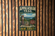 A vintage metal sign for the Appalachian Trail, featuring a scenic mountain landscape and the text "Appalachian Trail" and "The Journey is the Reward".