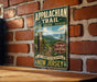 a vintage-style metal sign for the Appalachian Trail, mounted on a brick wall.