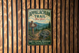 A vintage-style metal sign for the Appalachian Trail in New York, featuring a scenic mountain landscape and directional signs.