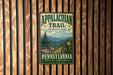 A vintage metal sign for the Appalachian Trail in Pennsylvania, featuring a scenic mountain landscape with a trail marker.