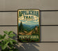 A vintage-style metal sign for the Appalachian Trail in Pennsylvania, featuring a scenic mountain landscape with a trail marker and the text "Appalachian Trail Pennsylvania" and "The Adventures Await".