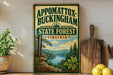 A vintage-style sign for Appomattox-Buckingham State Forest, Virginia, featuring a scenic landscape with pine trees, a river, and mountains.