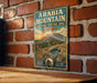 A vintage metal sign for the Arabia Mountain National Heritage Area in Georgia, featuring a scenic landscape with a mountain, desert, and a cactus.