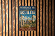a vintage-style metal sign with a colorful illustration of a historical site, such as the Patriarchal Basilica of Aquileia, Italy. The sign is mounted on a wooden wall and appears to be a travel advertisement promoting the archaeological and historical attractions of the area.