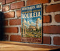 a vintage-style sign with a brick wall backdrop, advertising the archaeological area and the Basilica of Aquileia in Italy.