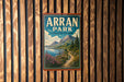 A vintage-style sign for Arran Park, United Kingdom, featuring a scenic mountain landscape with a winding path and a body of water.