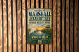 A vintage metal sign for the Loxahatchee National Wildlife Refuge in Florida, featuring a white egret and a sunset over a marsh.