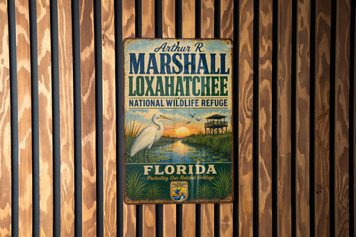 A vintage metal sign for the Loxahatchee National Wildlife Refuge in Florida, featuring a white egret and a sunset over a marsh.
