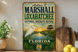 A vintage-style metal sign for the Florida Wildlife Refuge, featuring an illustration of a white egret and a sunset over a marsh.