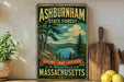 A vintage-style sign for Ashburnham State Forest, featuring a scenic landscape with pine trees, a lake, and mountains. The sign encourages visitors to explore, hike, and discover the natural beauty of Massachusetts.