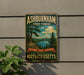 A vintage metal sign for Ashburnham State Forest, featuring a scenic landscape with pine trees, a lake, and mountains.
