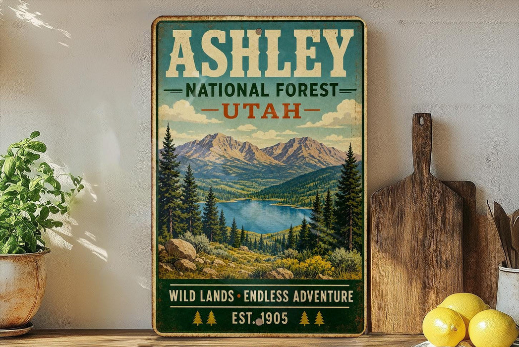 A vintage-style poster of the Ashley National Forest in Utah, featuring a scenic mountain landscape with pine trees and a lake.