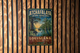 A vintage-style metal sign for the Atchafalaya National Heritage Area in Louisiana, featuring a scenic illustration of a bayou landscape with a bird and a boat.